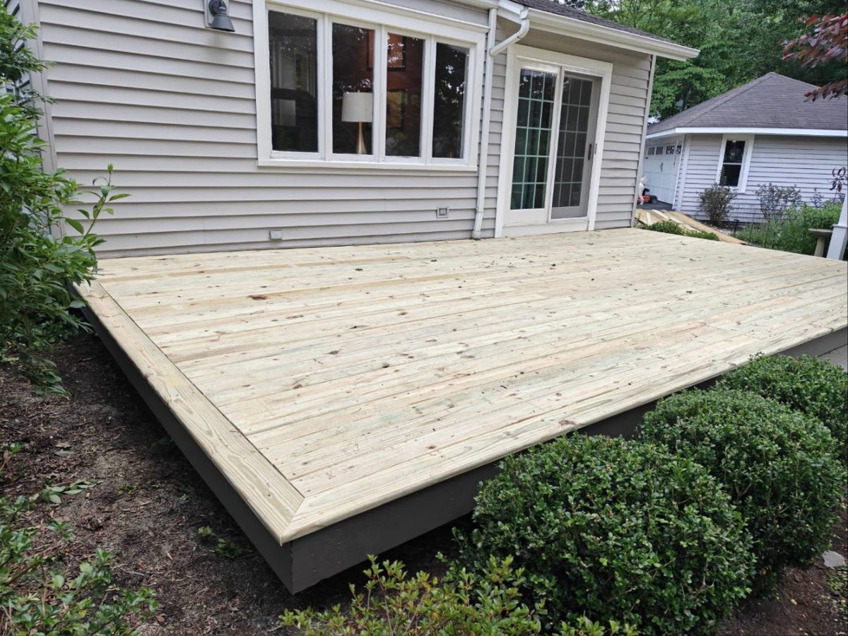 Finished pressure-treated deck with picture-frame border along the back of a house