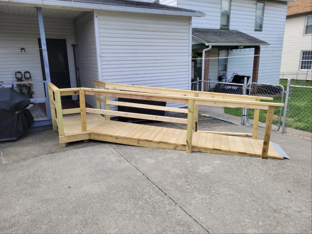 Wooden access ramp with railings leading to a back porch