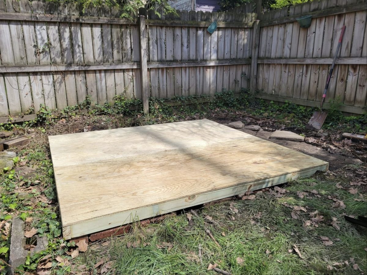 New plywood and pressure-treated shed foundation in a fenced backyard